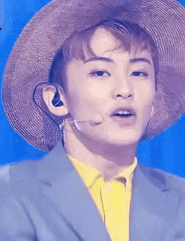a close up of a man wearing a hat and earbuds