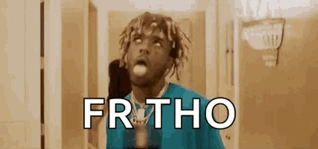 a man with dreadlocks is standing in front of a door with his mouth open and the word frtho written on the screen .