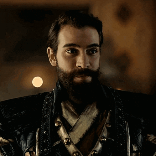 a man with a beard and mustache wears a black jacket