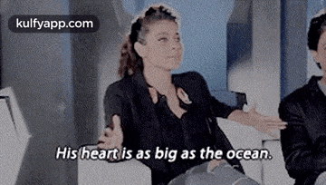 a woman is sitting next to a man and says `` his heart is as big as the ocean . ''