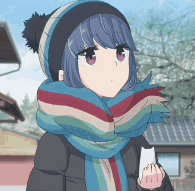 a girl wearing a hat and scarf is holding a piece of paper in her hand .