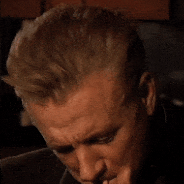 a man in a suit is lighting a cigarette with his hand .