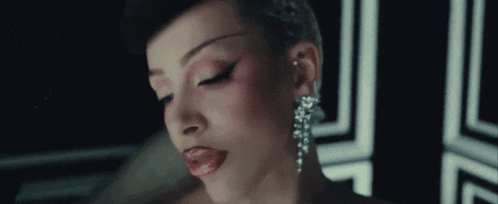 a close up of a woman 's face wearing earrings and red lipstick .