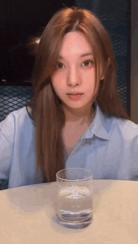 a young girl is sitting at a table with a glass of water .