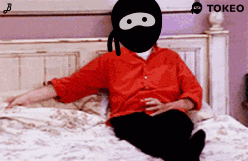 a man in a red shirt is sitting on a bed with a tokeo logo in the corner