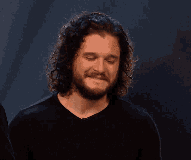 a man with curly hair and a beard is smiling