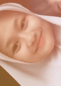 a close up of a young girl wearing a white hijab .