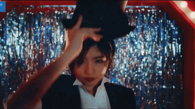 a woman in a tuxedo is holding a top hat on her head ..