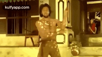 a man without a shirt is standing in front of a building in a room .