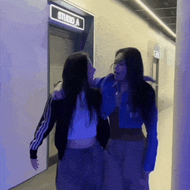 two women standing in front of a studio a door