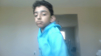 a young boy in a blue hoodie is standing in front of a window