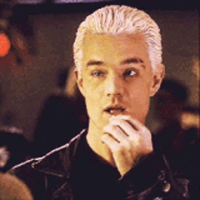 a man with blonde hair is wearing a black shirt and a black jacket