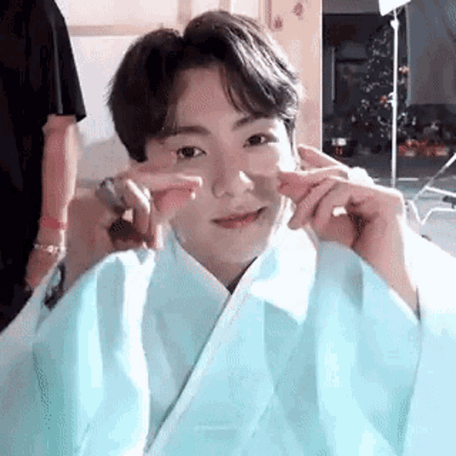 a close up of a person wearing a blue kimono and making a peace sign .