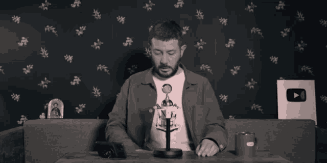 a man sitting at a table wearing a t-shirt that says ' a.d.a. ' on it