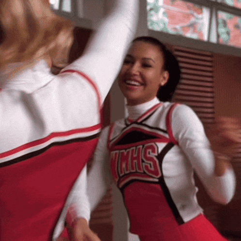 two cheerleaders wearing red and white uniforms with the word mhs on them