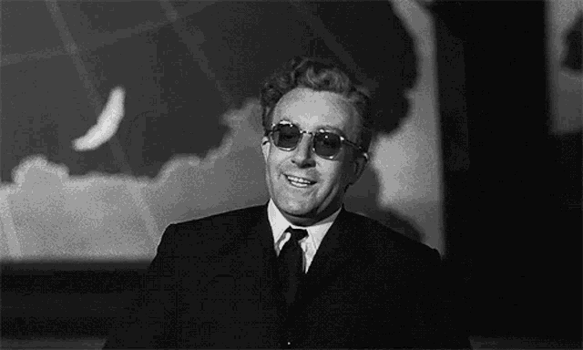 a black and white photo of a man wearing sunglasses and a suit