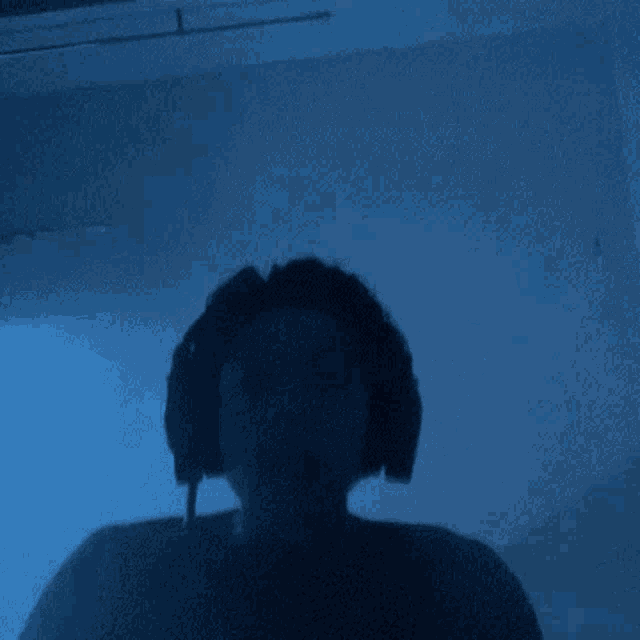 a man without a shirt is standing in a dark room with his arms outstretched .