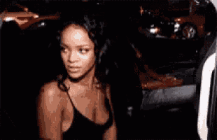 a woman in a black tank top is standing in a car .