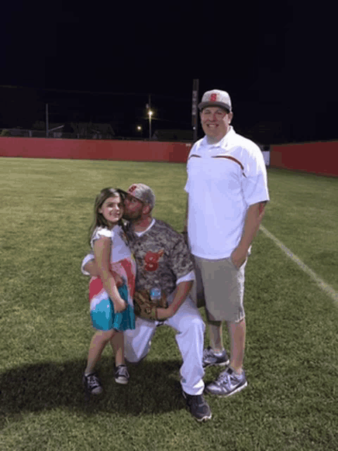 a man kisses a little girl on the cheek while two other men stand behind him