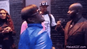 a man in a blue jacket is talking to another man in a suit .
