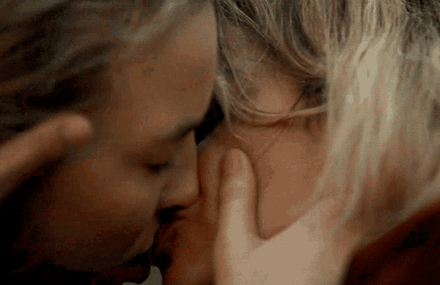 a close up of a woman kissing another woman 's face