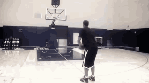 a man is playing basketball in a gym with a scoreboard that says 88