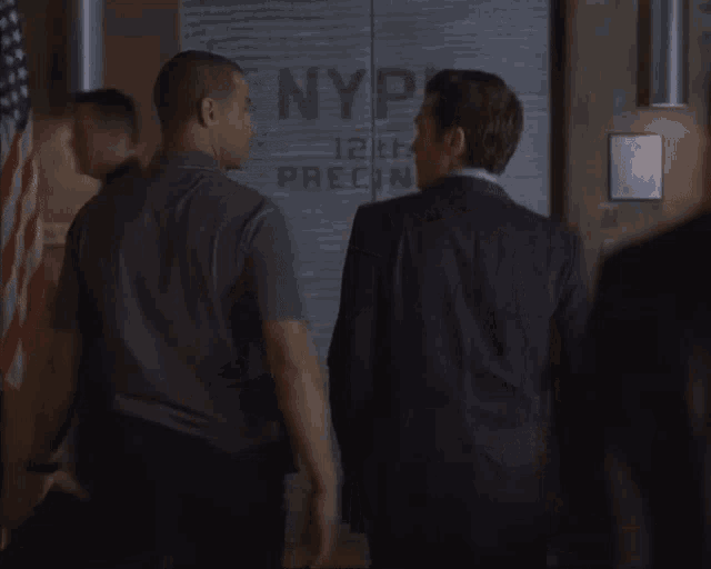 two men are standing in front of a wall that says nypd on it