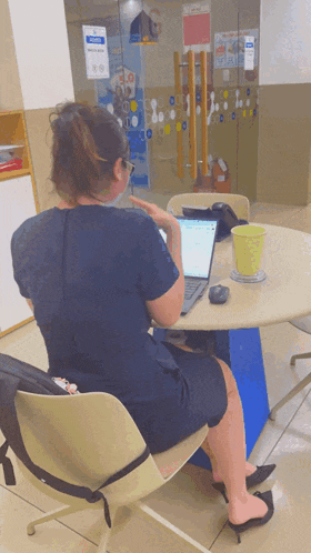 a woman is sitting at a table with a laptop and a cup of coffee