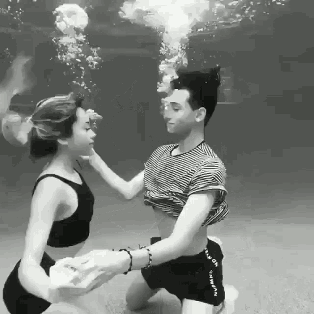 a black and white photo of a man and a woman under water