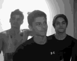 a group of young men are standing next to each other in a room in a black and white photo .