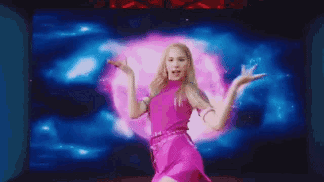 a woman in a pink dress is dancing on a stage with a blue background .