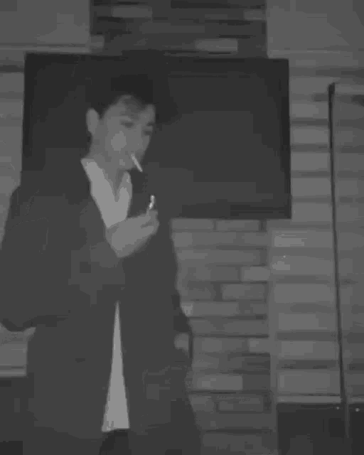 a black and white photo of a person smoking a cigarette .