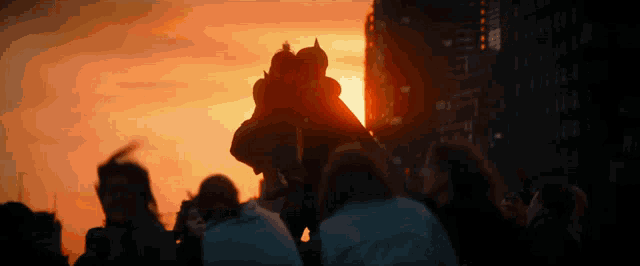 a group of people are gathered in front of a sunset skyline