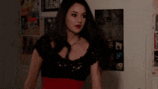 a woman in a black dress is standing in front of a wall with a poster on it .