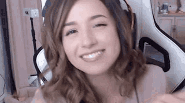 a woman wearing headphones is smiling while sitting in a gaming chair .