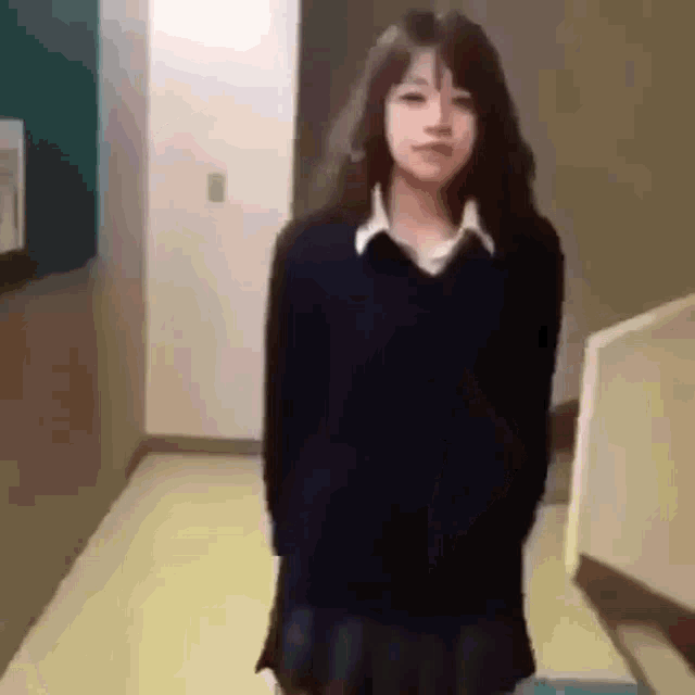 a girl in a school uniform is standing in a hallway next to a staircase .