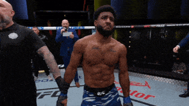 a man with a tattoo on his chest is standing in a ufc ring