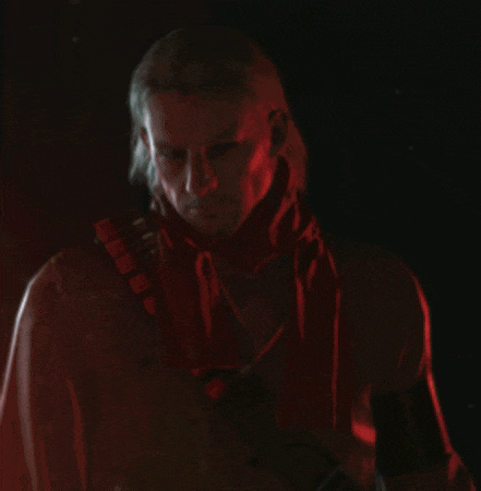 a man with a red scarf around his neck holds a rifle