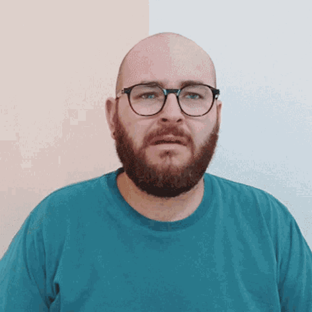 a bald man with a beard wearing glasses is making a funny face