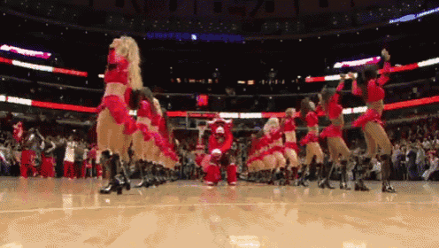 a group of cheerleaders are performing on a basketball court and one of them is dressed as santa claus