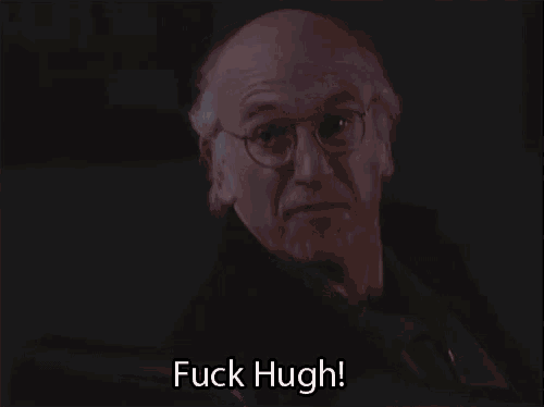 a man with glasses is saying fuck hugh in a dark room