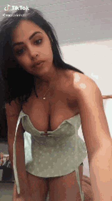 a woman is taking a selfie with her breasts exposed in a green dress .