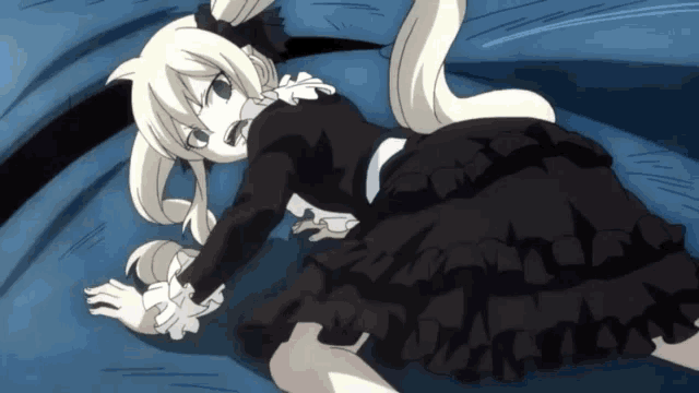 a girl in a black dress is laying on a blue blanket