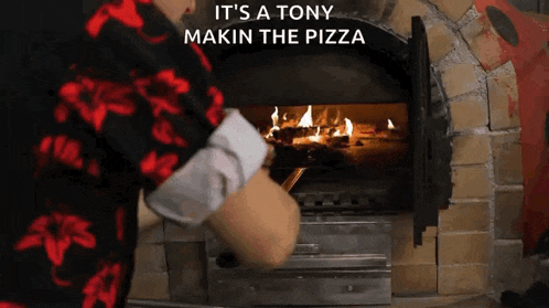 a person in a red shirt is putting a pizza in an oven with the words it 's a tony makin the pizza