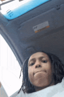a young man with dreadlocks is taking a selfie in a car