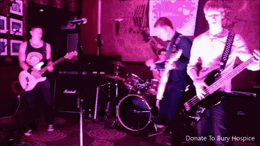 a man playing a guitar in front of a sign that says donate to bury hospice on it