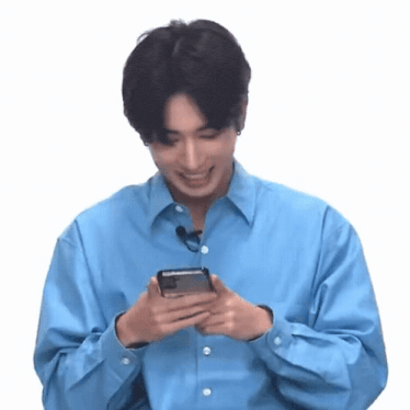 a man in a blue shirt is holding a cell phone in his hands .