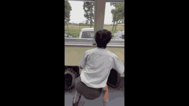 a man squatting in front of a window looking out