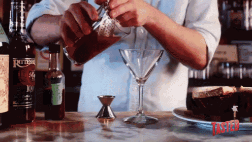 a bartender pours a drink into a martini glass next to a bottle of pottenni