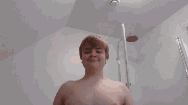 a shirtless young man is flexing his muscles in a bathroom